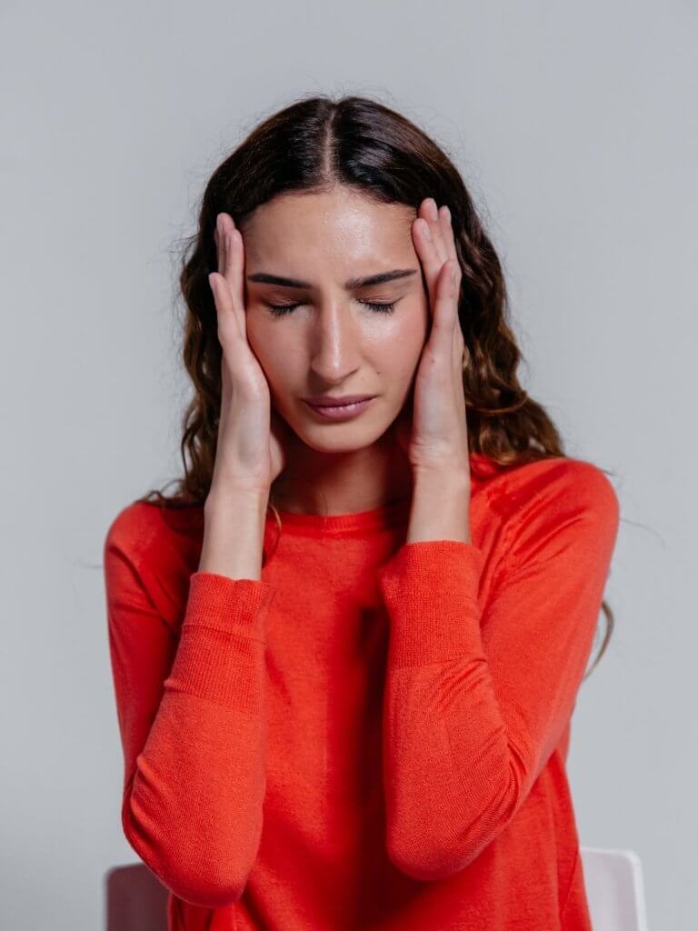 Femme pensive et anxieuse, main sur le front, illustrant la rumination mentale - Esprit Primavera Toulouse